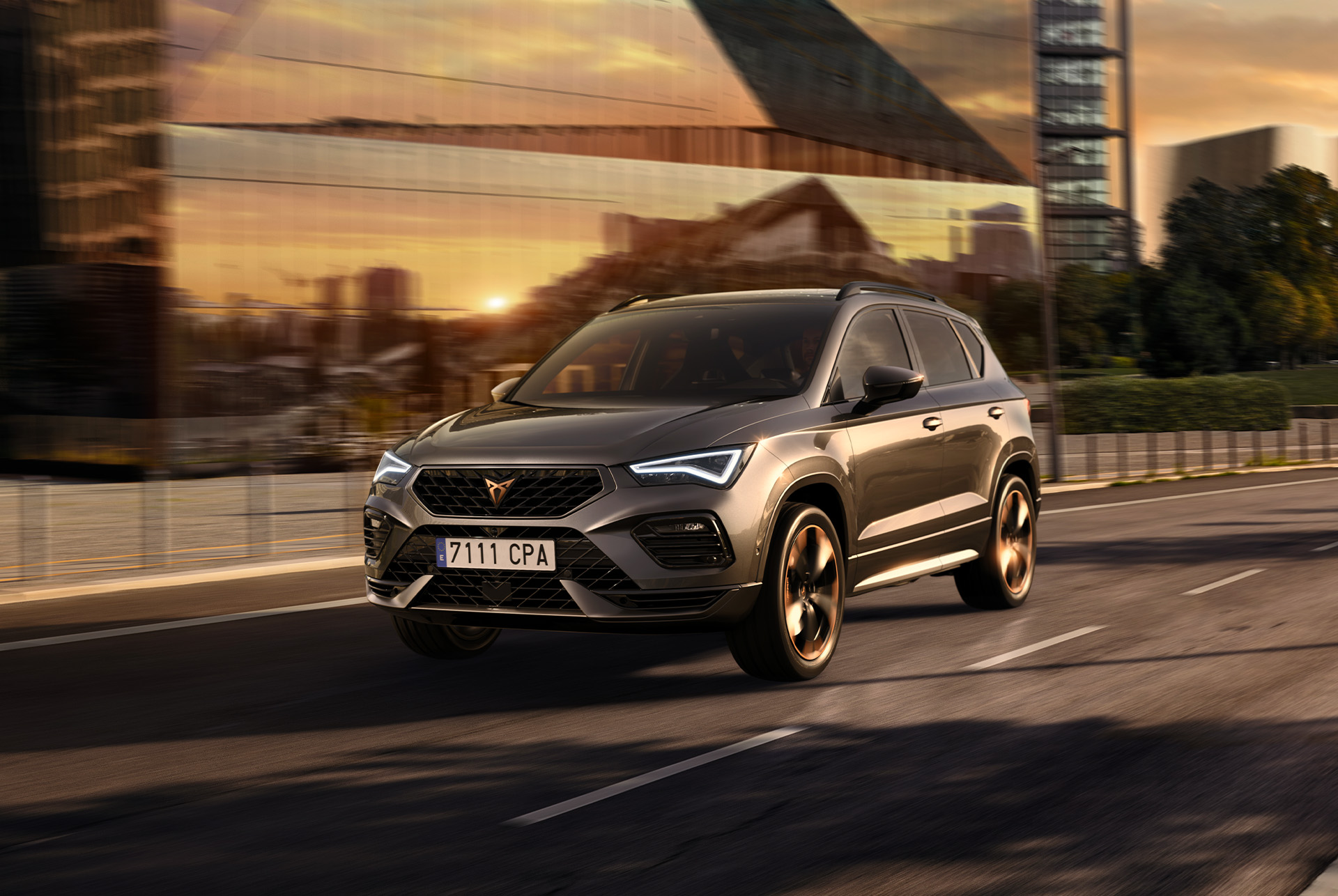 Le SUV CUPRA Ateca roule sur une route urbaine au coucher du soleil. Le SUV est disponible avec des moteurs de 150 ch et 190 ch avec 4 roues motrices, ce qui permet de réduire les émissions et la consommation de carburant. 