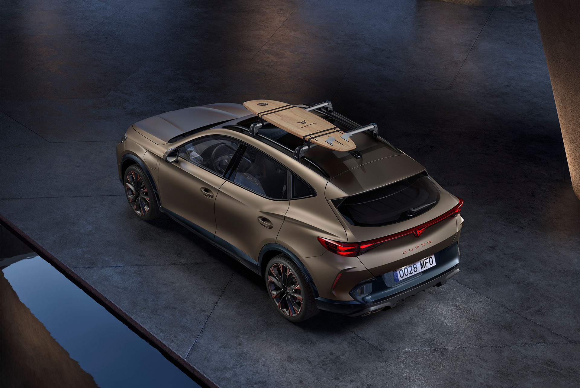 Vue aérienne du CUPRA Formentor 2024 century bronze matt avec un accessoire de support de planche de surf sur le toit de la voiture, voiture garée.