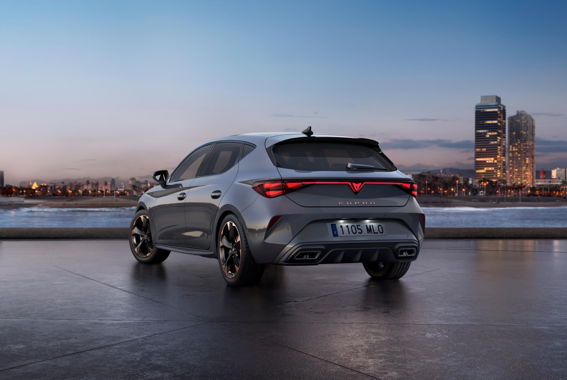 Vue arrière de la nouvelle Cupra Leon 2024 gris brillant avec contrôle dynamique du châssis et jantes en alliage noir et cuivre. Ville en arrière-plan au coucher du soleil.