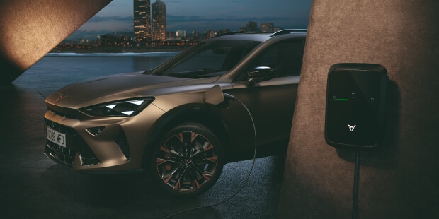 plug-in hybrid electric vehicle, cupra formentor plugged into wallbox, charging at concrete setting with city skyline backdrop